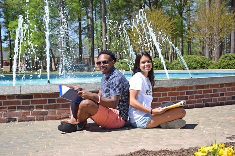students studying outside in front of fountain